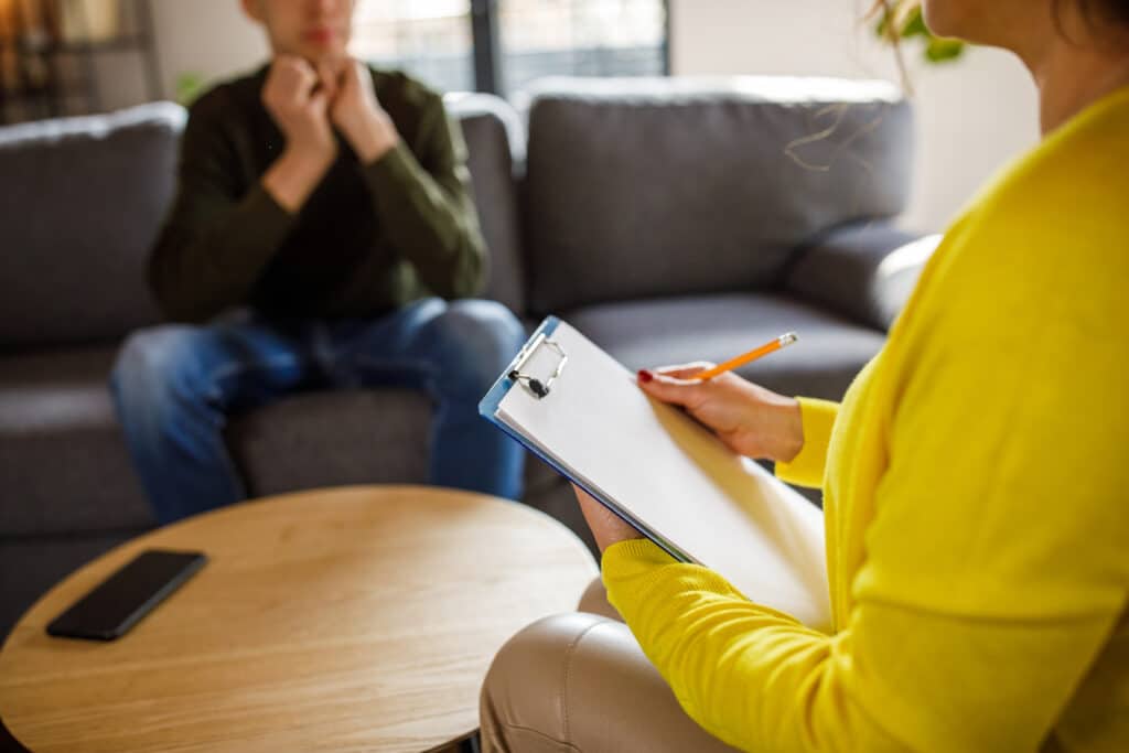 Caring female therapist talking with teenage boy about opiate Addiction