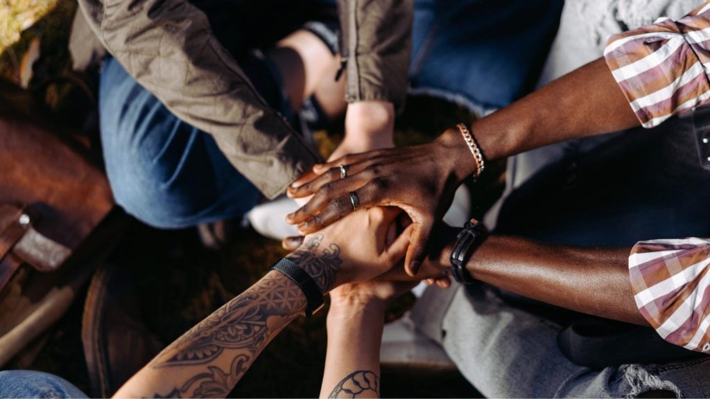 Group of people putting their hands together to show support during intensive outpatient treatment.