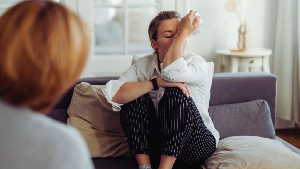 Person sitting with therapist, showing emotional distress related to Adderall addiction symptoms