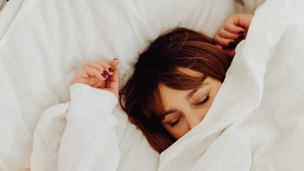 Person resting in bed, illustrating fatigue and sleep disruption linked to irritability on Adderall.