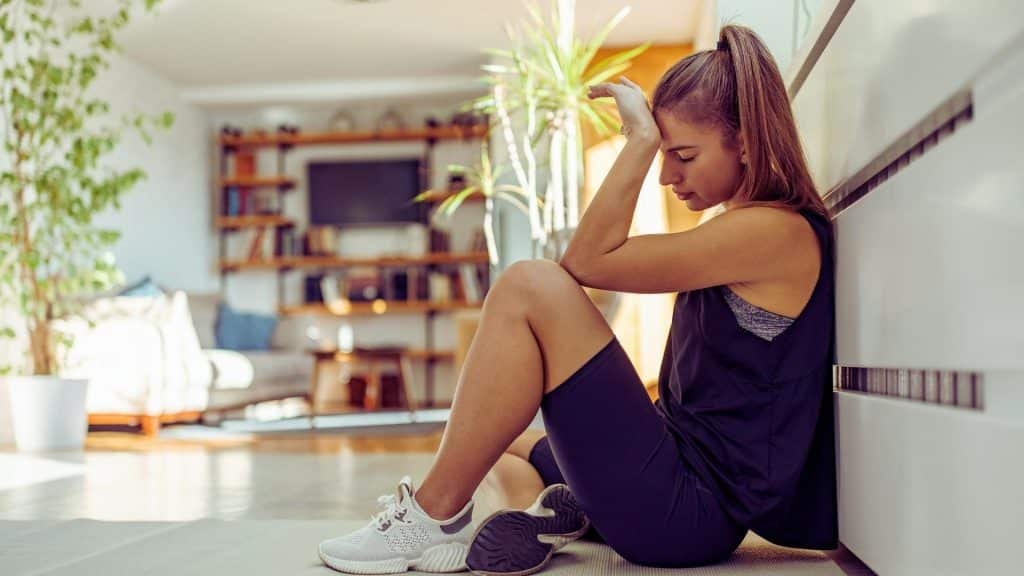 Woman sitting on floor feeling nauseous from cannabinoid hyperemesis syndrome symptoms