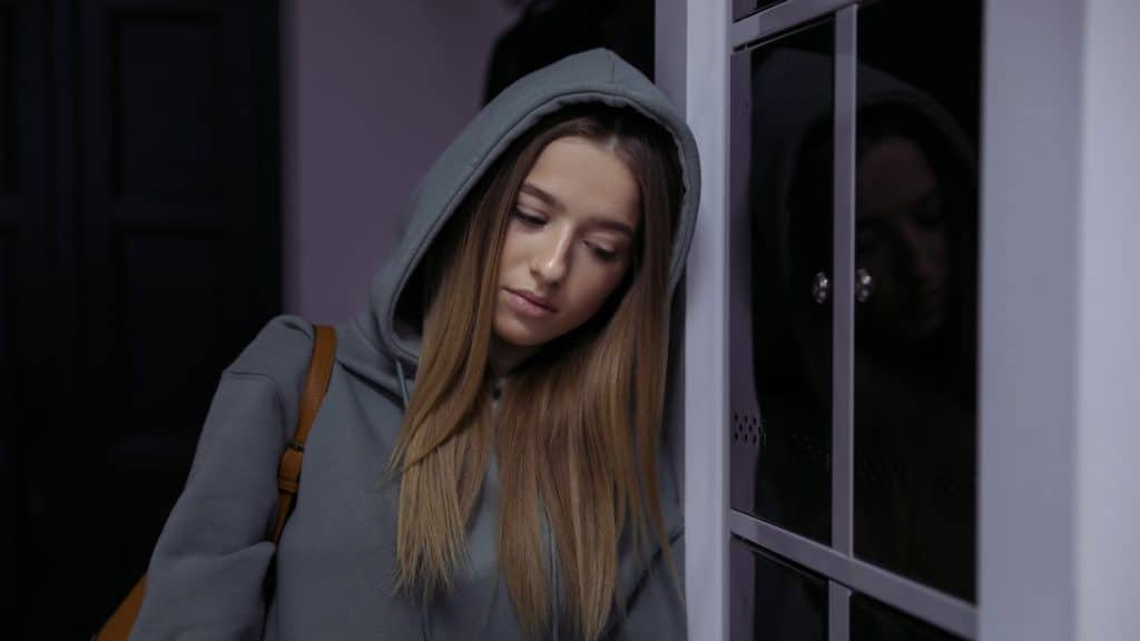 Woman leaning against wall looking fatigued during CHS recovery after quitting marijuana