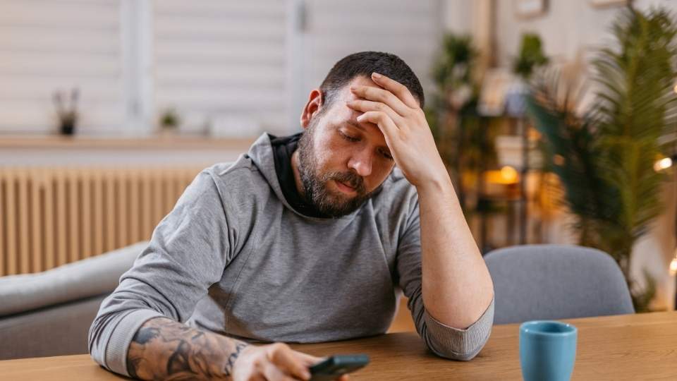 Is Adderall Addictive a man looks down at his phone while feeling dependent on the drug.