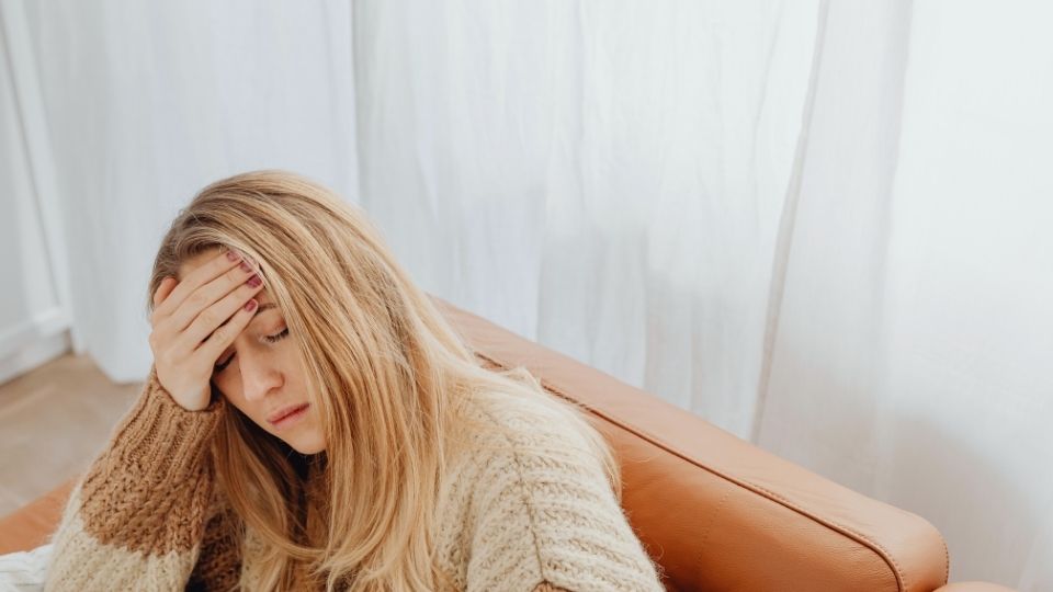 Vivitrol Side Effects hero image of a woman experiencing a headache.