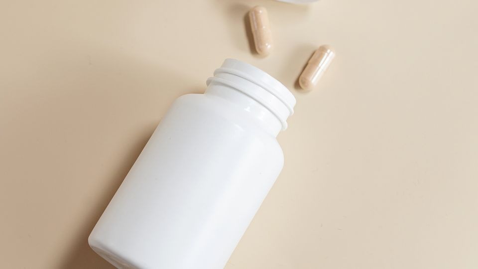 Prescription stimulant capsules and pill bottle on a counter illustrating how long does Adderall stay in your system.