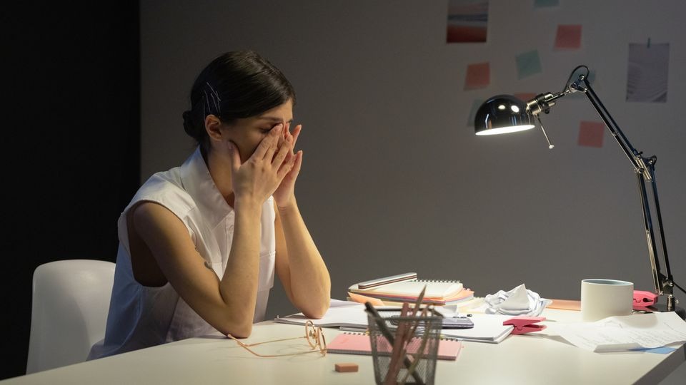 Professional slumped at a desk in the late afternoon, showing how long does Adderall stay in your system after effects fade
