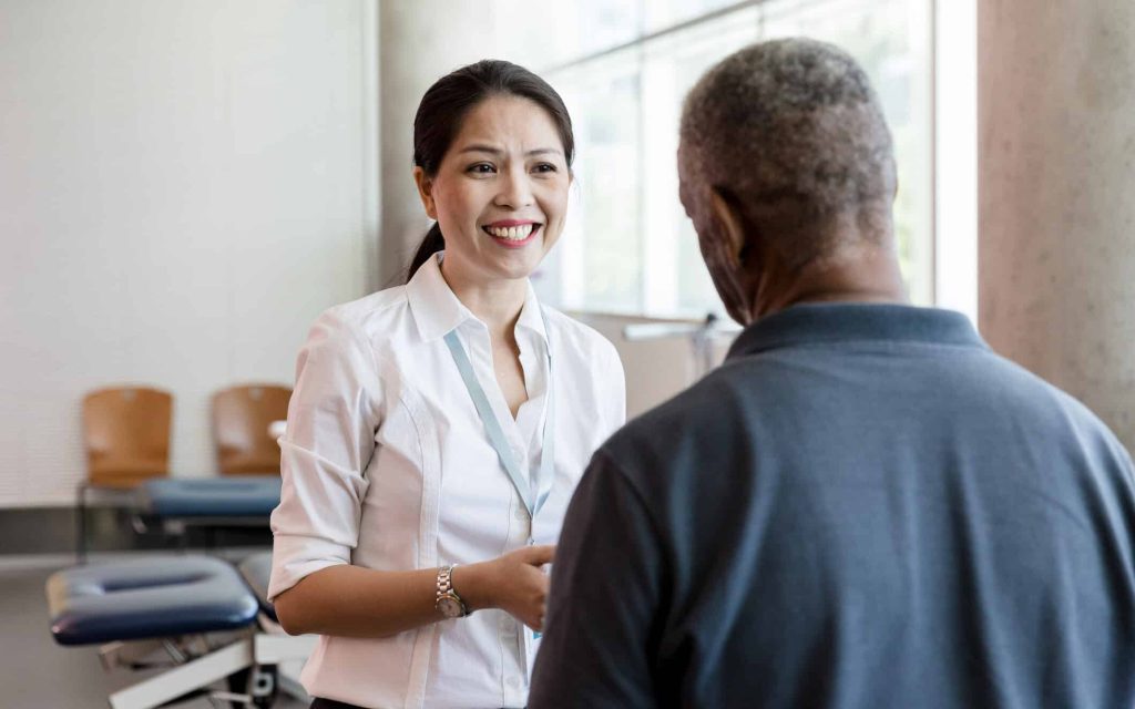 A smiling clinician greeting an older patient in a medical office