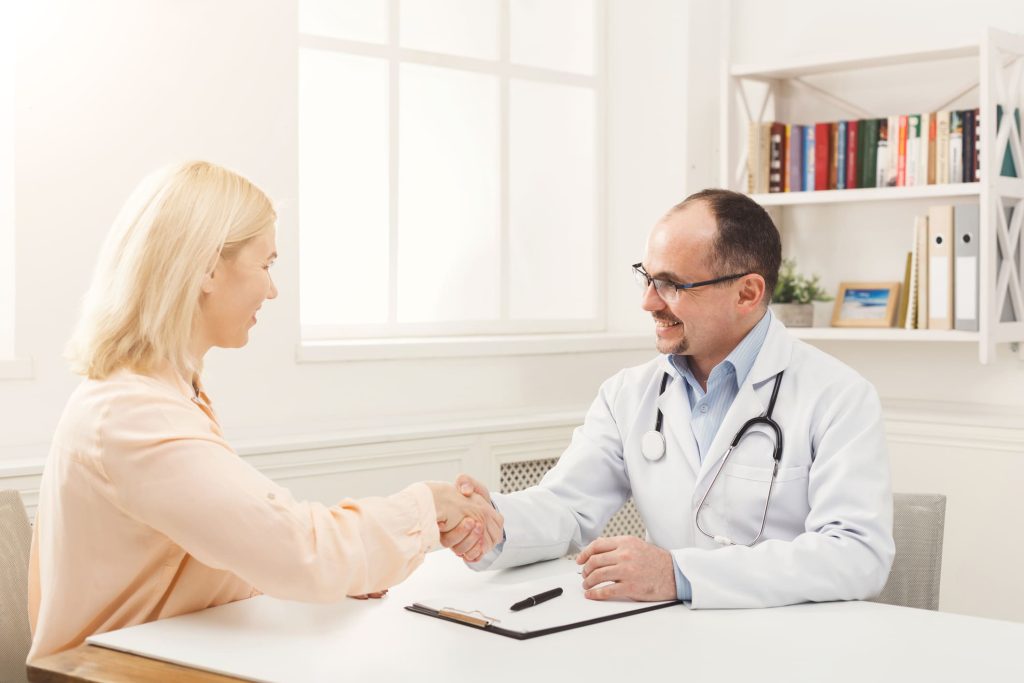 A doctor shaking hands with a patient at the start of an appointment
