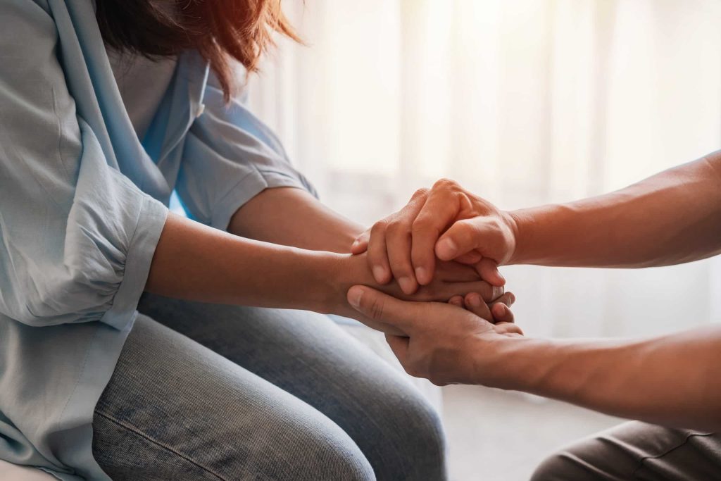 Two people holding hands in a gesture of support