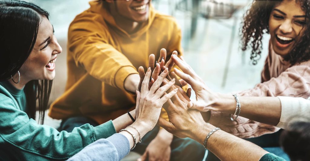 A group of people joining hands in the center of a circle